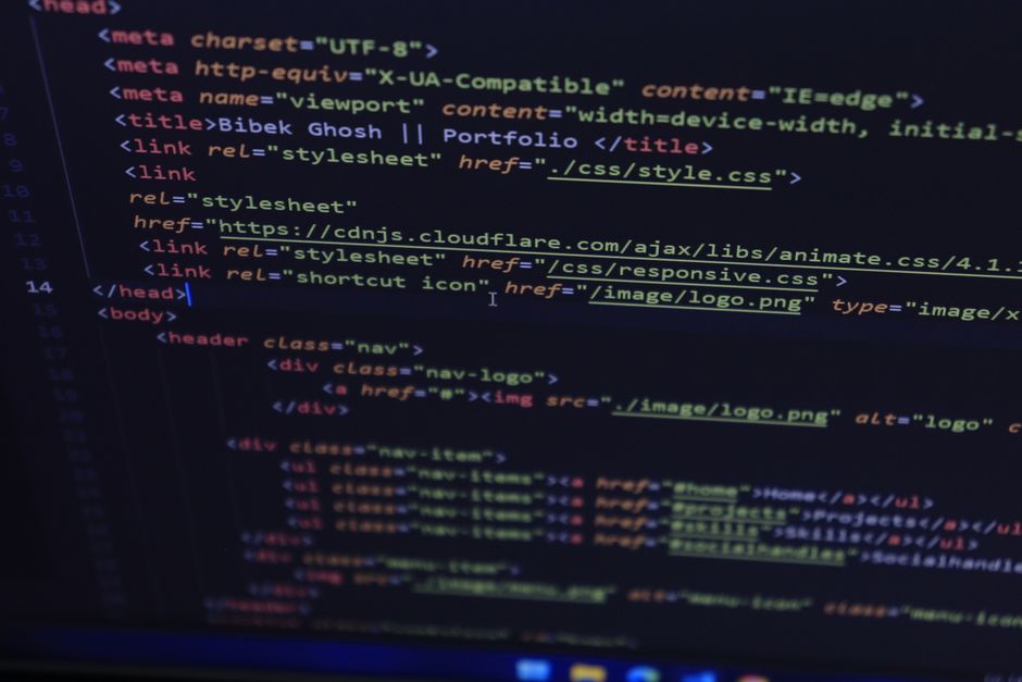 A close-up of a laptop computer screen displaying lines of XML or HTML code on the left side of the screen, with a modern, flat-design orange calculator interface on the right side featuring large but